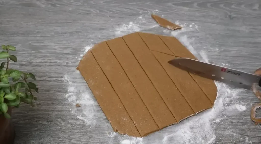 cutting mung kevum dough into strips before frying