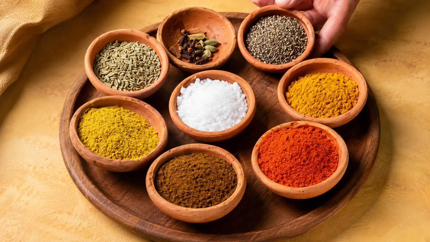 Sri Lankan curry spices in clay bowls with turmeric, chili powder, salt, fennel seeds, pepper, cloves and cardamom