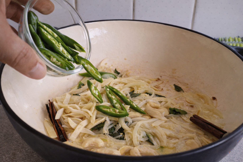 Add cinnamon, curry leaves, pandan leaves and onion