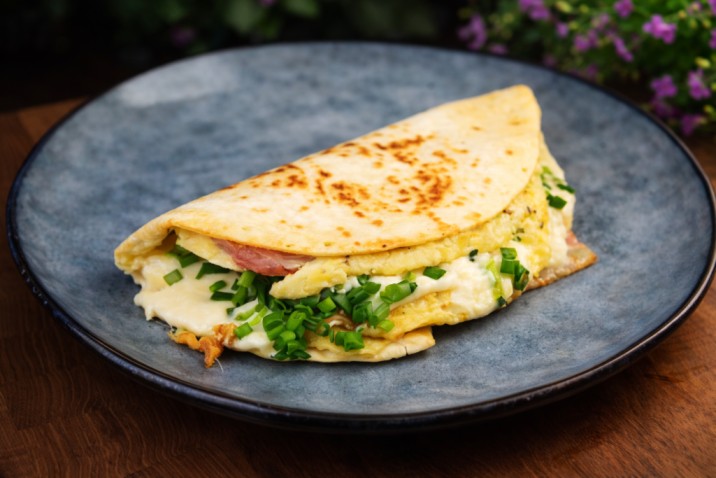 cheesy omelette tortilla wrap with green onions served on a plate