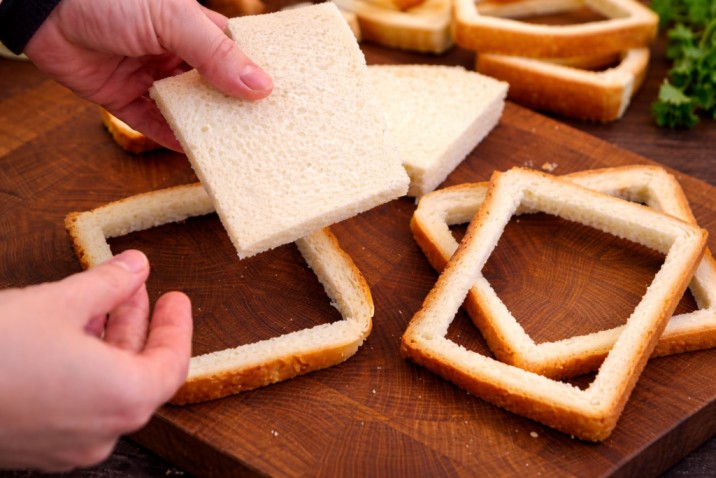 removing the center of bread slices to prepare bread rolls