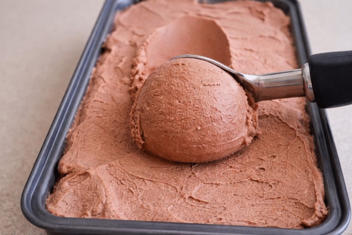 scooping homemade chocolate ice cream from tray with ice cream scoop