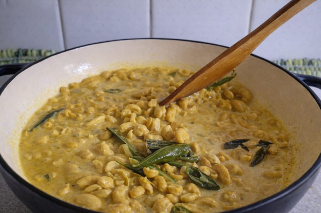 Sri Lankan cashew curry simmering in coconut milk with curry leaves in a pan