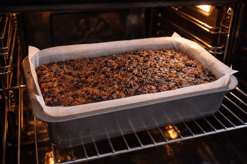 Sri Lankan Christmas cake baking in oven in a tray with rich fruit mixture