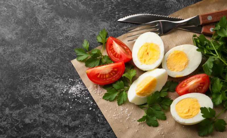 boiled eggs sliced with tomato and herbs on a board