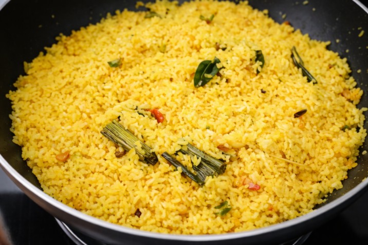 yellow rice cooked with spices and curry leaves in a pan