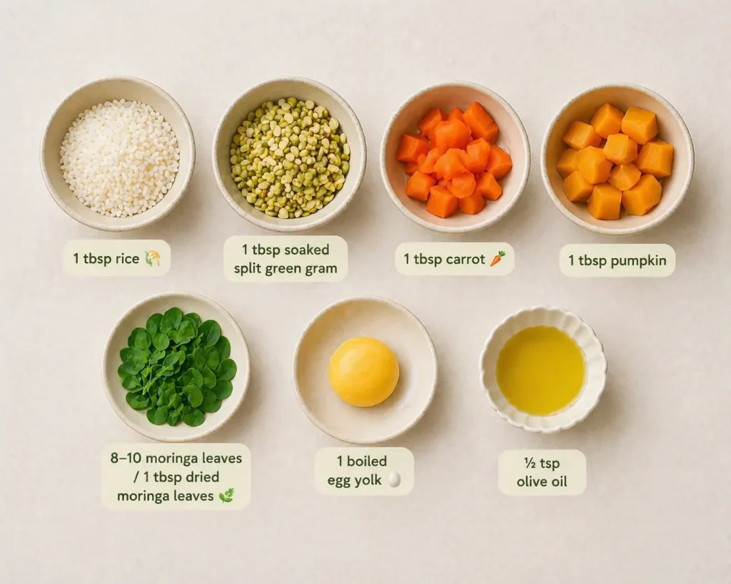 Baby food ingredients including rice, soaked split green gram, carrot, pumpkin, moringa leaves, boiled egg yolk, and olive oil arranged neatly in bowls