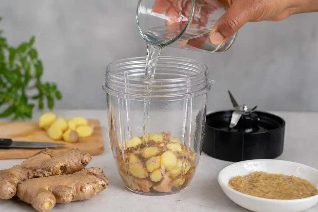 Fresh ginger pieces being blended with water to make ginger paste