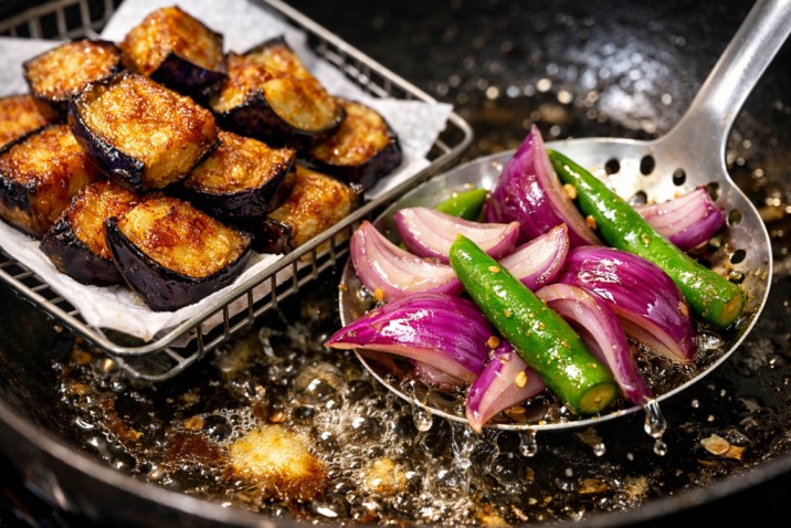 frying eggplant pieces, onions, and green chilies in hot oil for Sri Lankan wambatu pahi