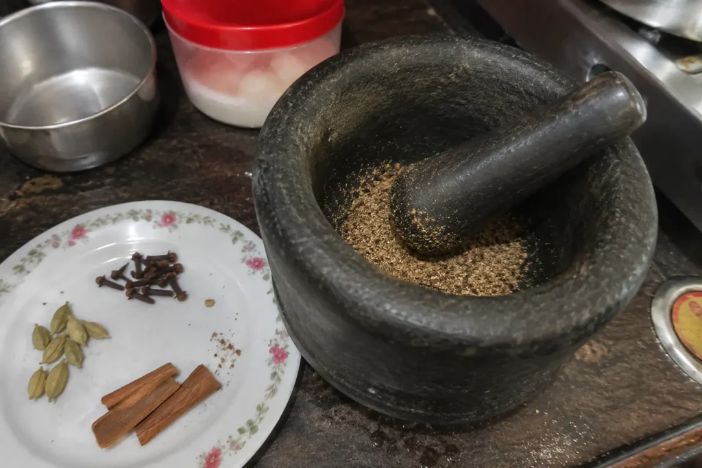 grinding cardamom cloves and cinnamon for homemade watalappam